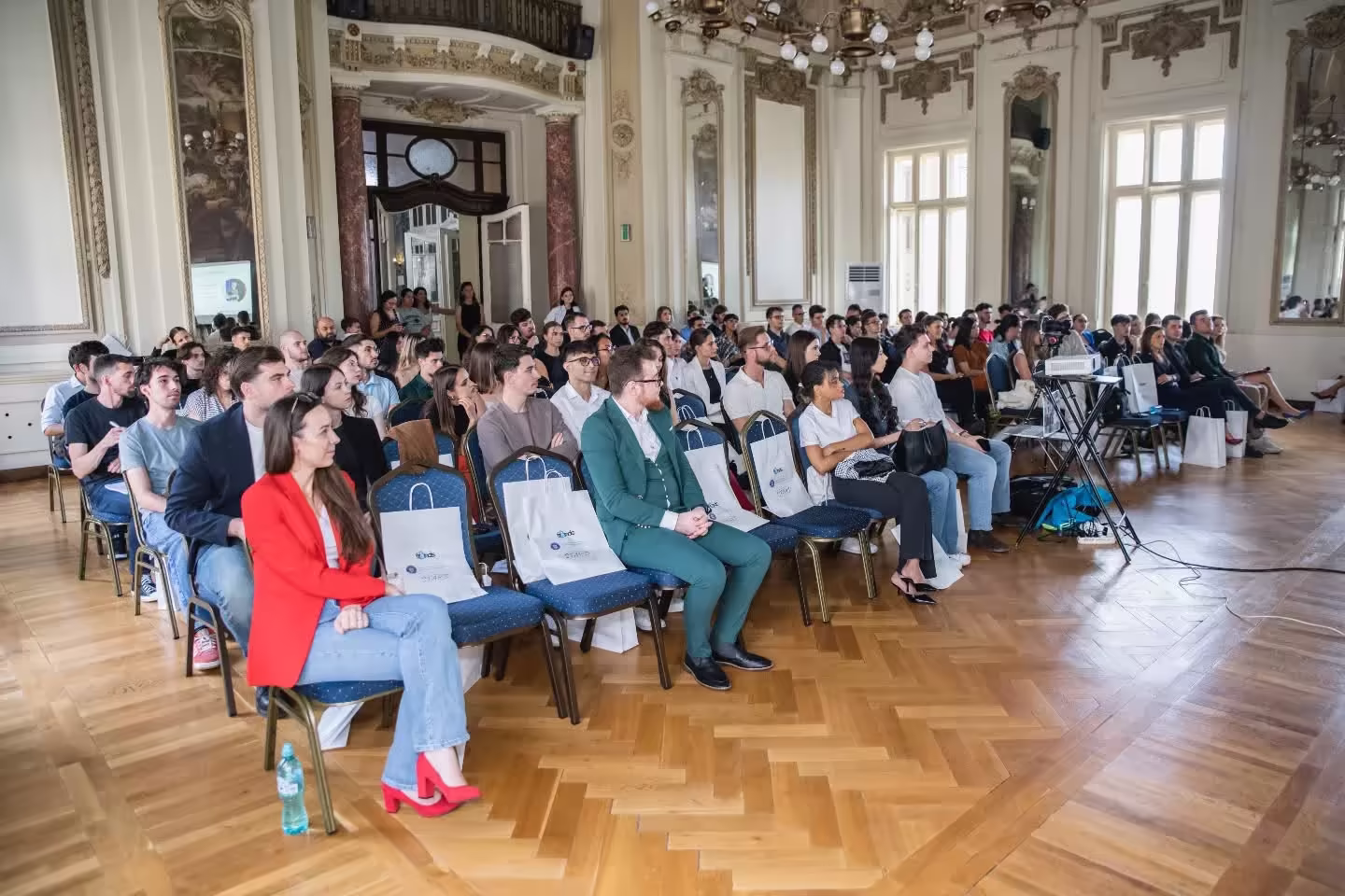 Participanții la START într-o sală festivă, urmărind prezentările